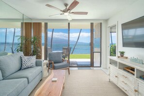 Enjoy ocean views from the large window in this stylish living room, featuring a sofa, coffee table, and mounted TV.