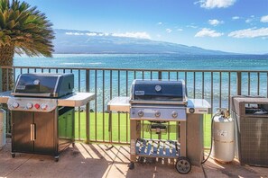 Enjoy al fresco dining with a view of the ocean and distant mountains from your balcony, featuring two gas grills and a wicker basket.