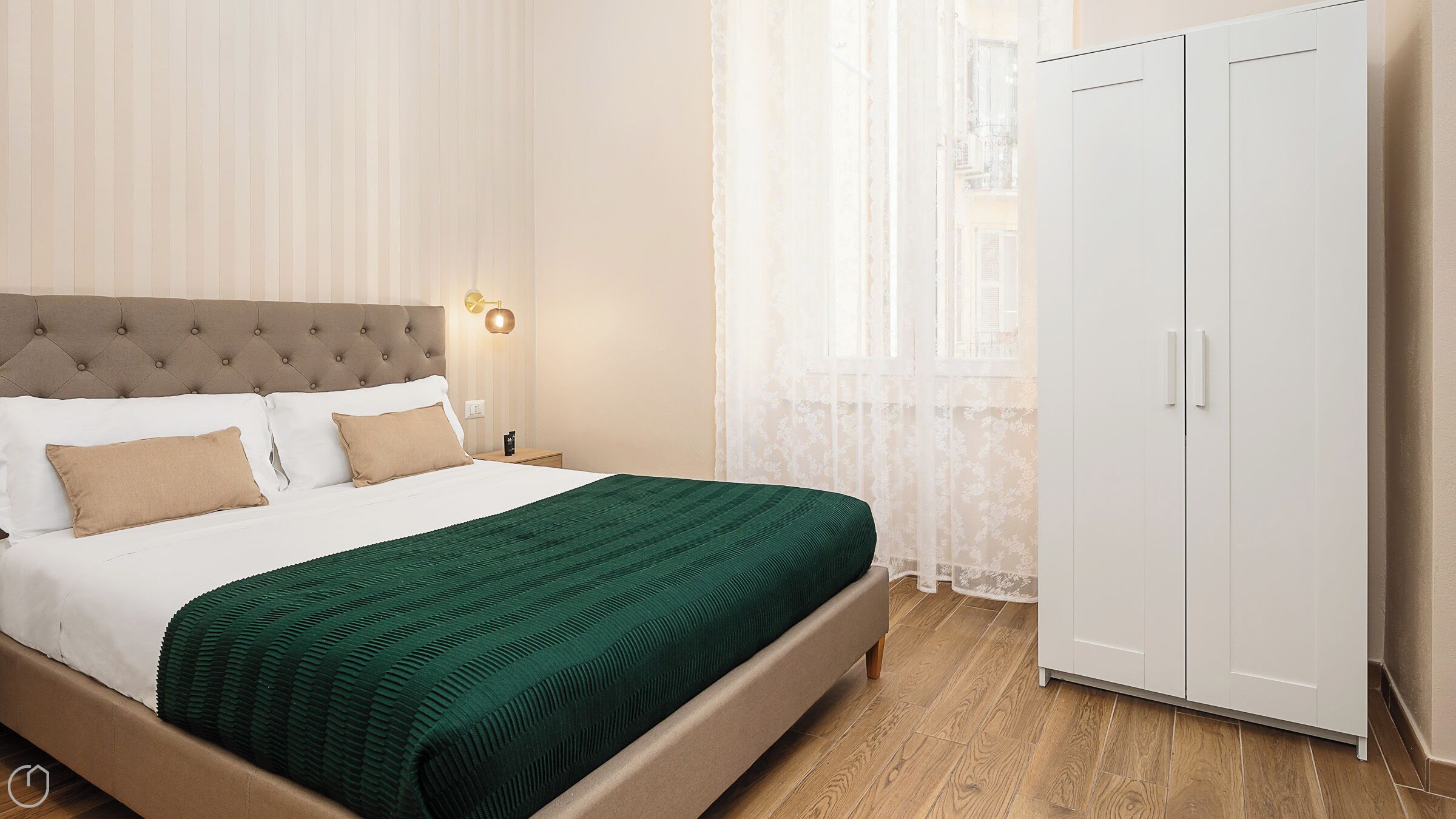 A neatly arranged bedroom with a bed, nightstand, and wardrobe.
