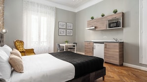 A bedroom with a bed, a desk, a chair, and a kitchenette. - Italianway - Monza 39 (Milan)