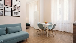 A modern living room with a blue sofa, a dining table with chairs, and a white cabinet. - Italianway - Monza 39 (Milan)
