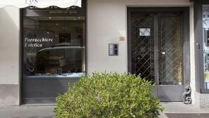 Una vetrina con un cartello che riporta 'Parrucchieri Estetica' e il numero '33' sopra la porta.