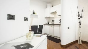Una cucina moderna con mobili bianchi, un piano di lavoro nero e un'area pranzo con tavolo e sedie bianche.