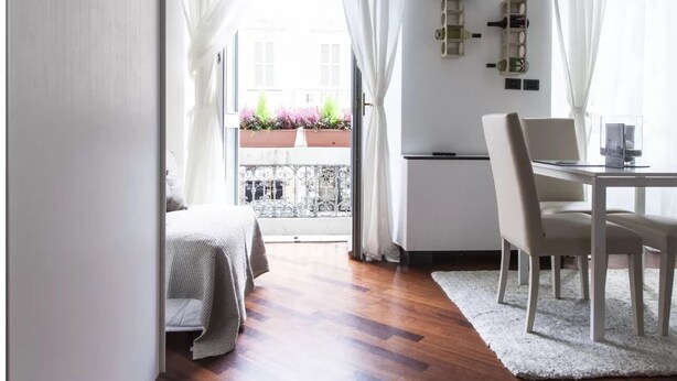 Una camera moderna con un letto, un tavolo da pranzo con sedie e un balcone con piante.