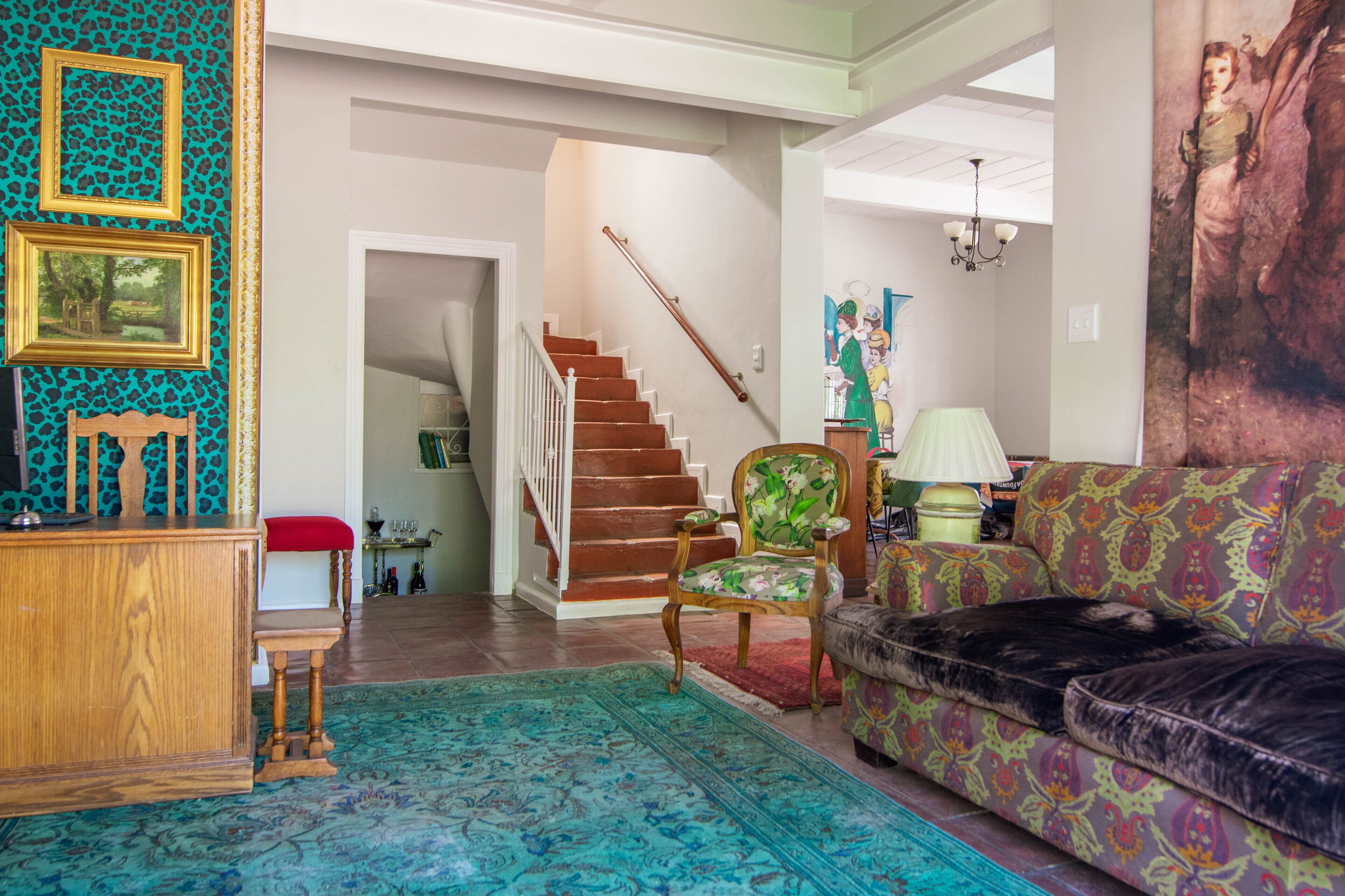 A living room with a staircase, a sofa, a chair, and a rug.