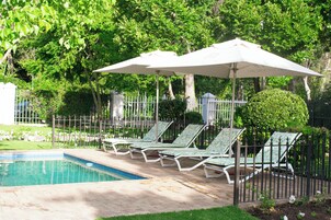 Una piscina al aire libre, sillones reclinables de piscina