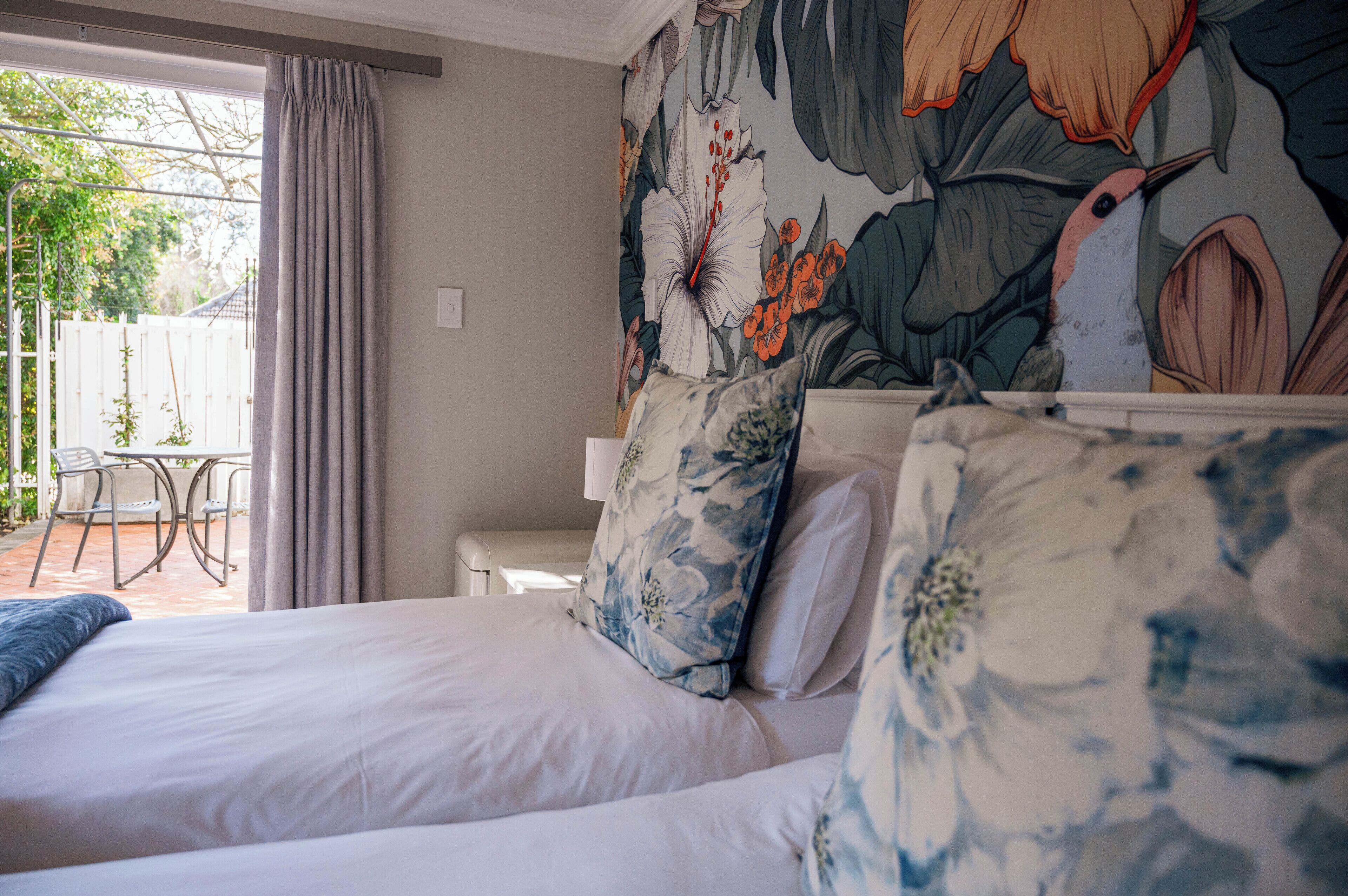 A bedroom with a large bed, a nightstand, and a floral mural on the wall.
