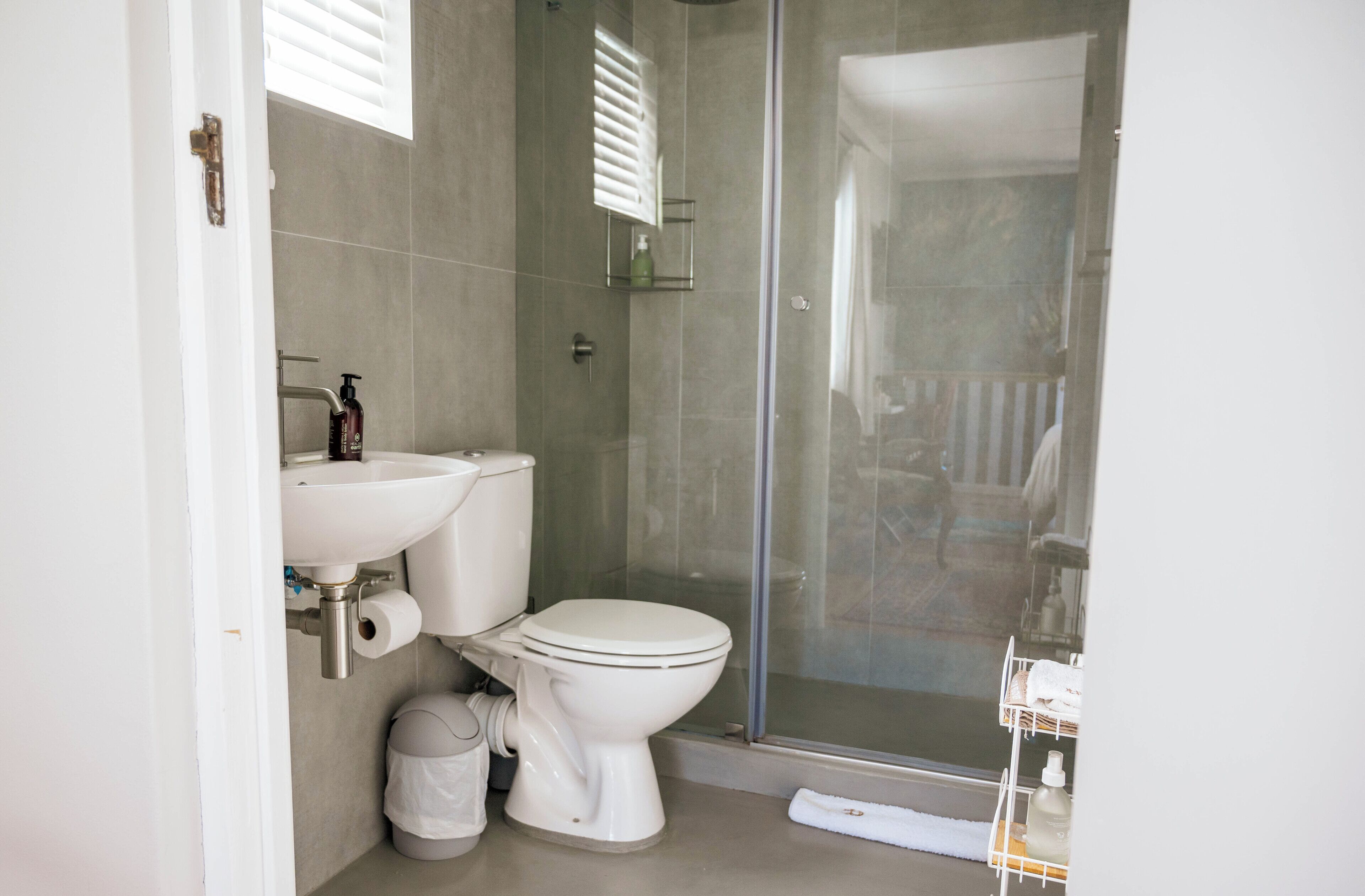 Een moderne badkamer met toilet, wastafel en douche.