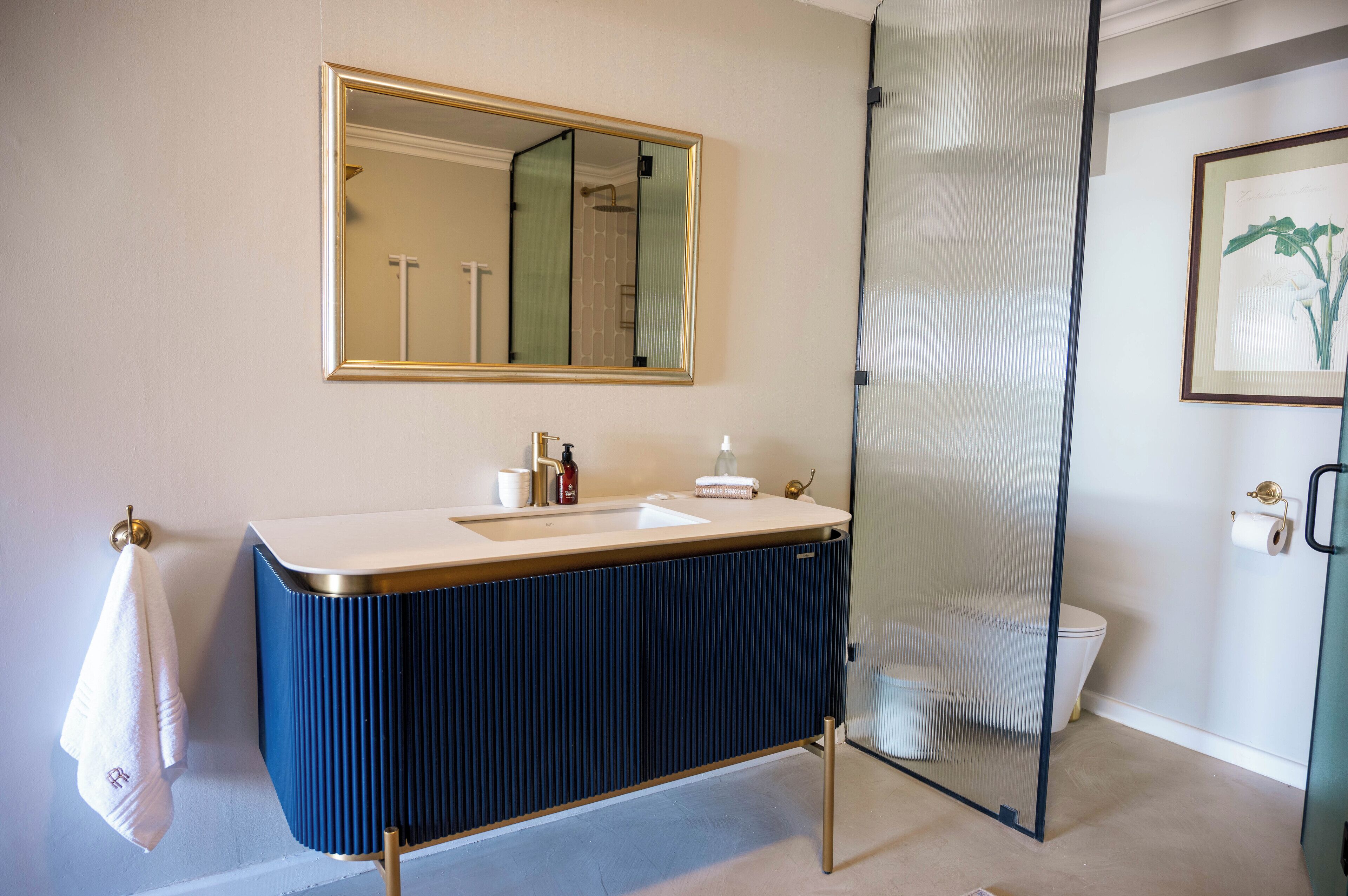 A modern bathroom with a large mirror, a sink, and a toilet.