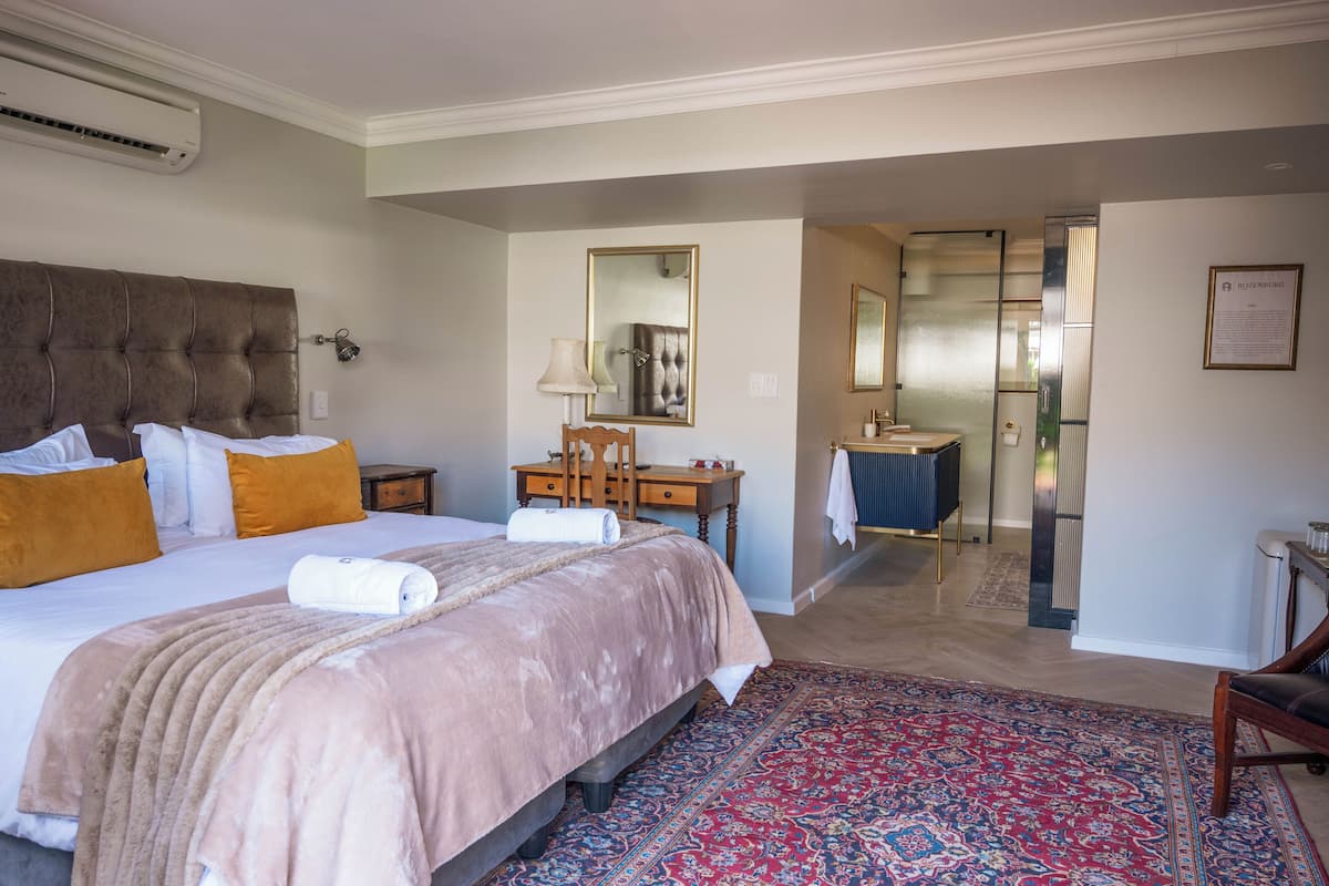 Habitación de hotel con una cama grande, un escritorio, una silla, un espejo y un ascensor.