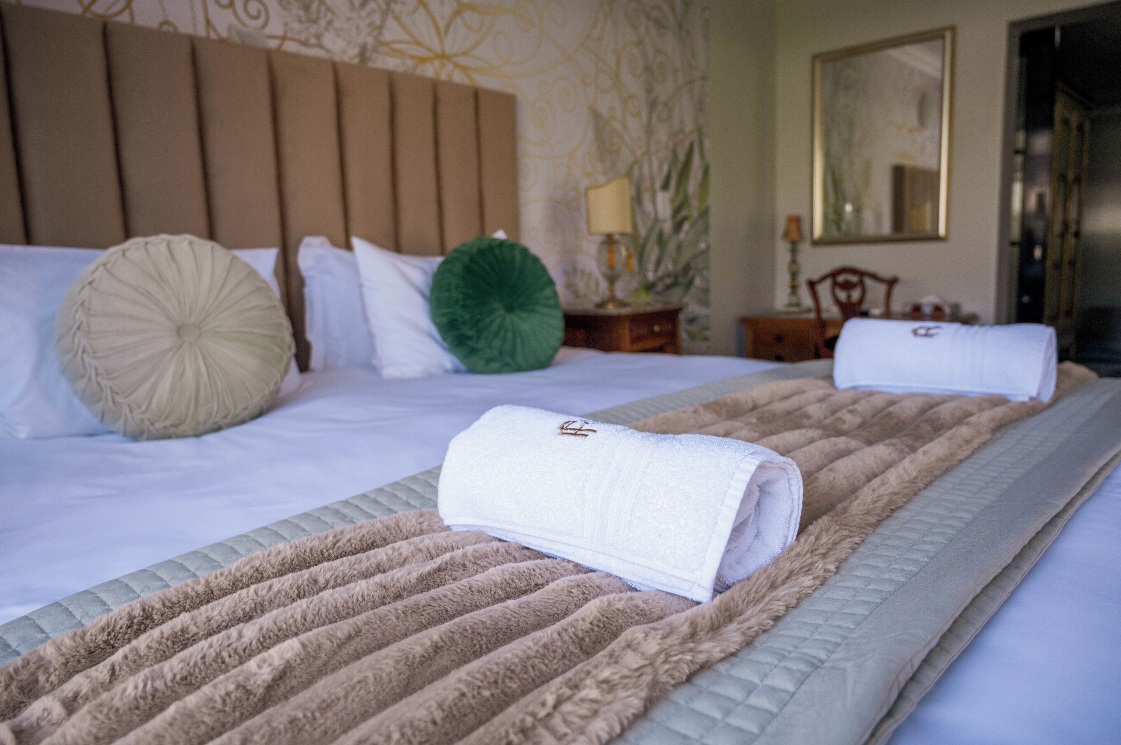 A neatly made bed with a beige headboard, a fluffy beige blanket, and a green decorative pillow.