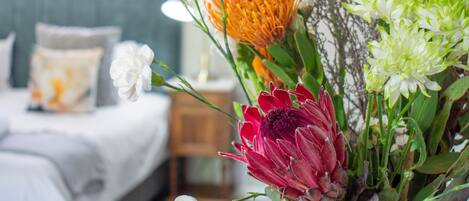 A room with a bed, a bedside table, and a vase of flowers.