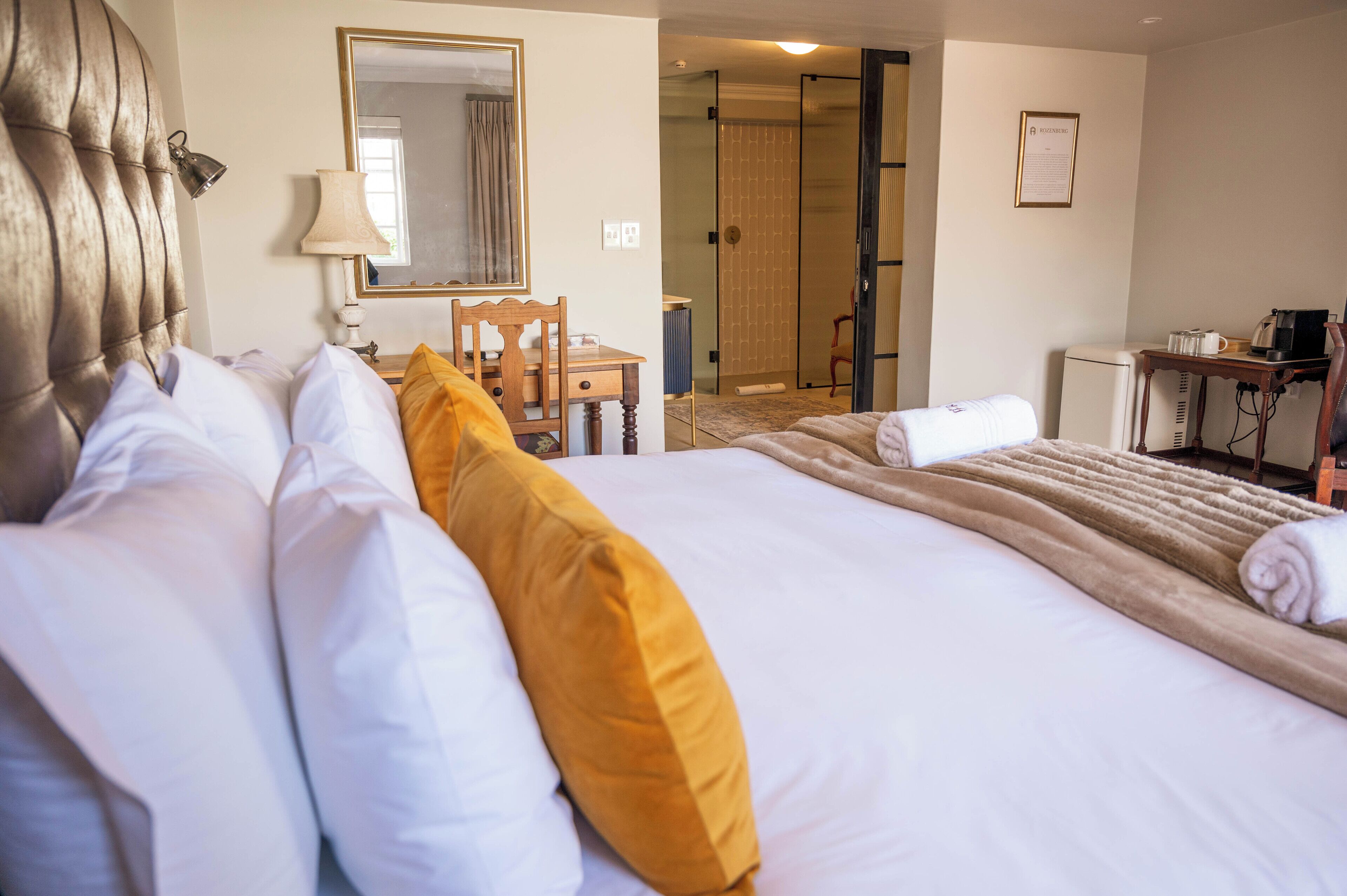 Une chambre d’hôtel avec un grand lit, un bureau, une chaise, un miroir et une salle de bain avec douche.