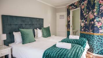 Quarto de hotel com uma cama grande, duas almofadas, mesa de cabeceira com abajur e um espelho.
