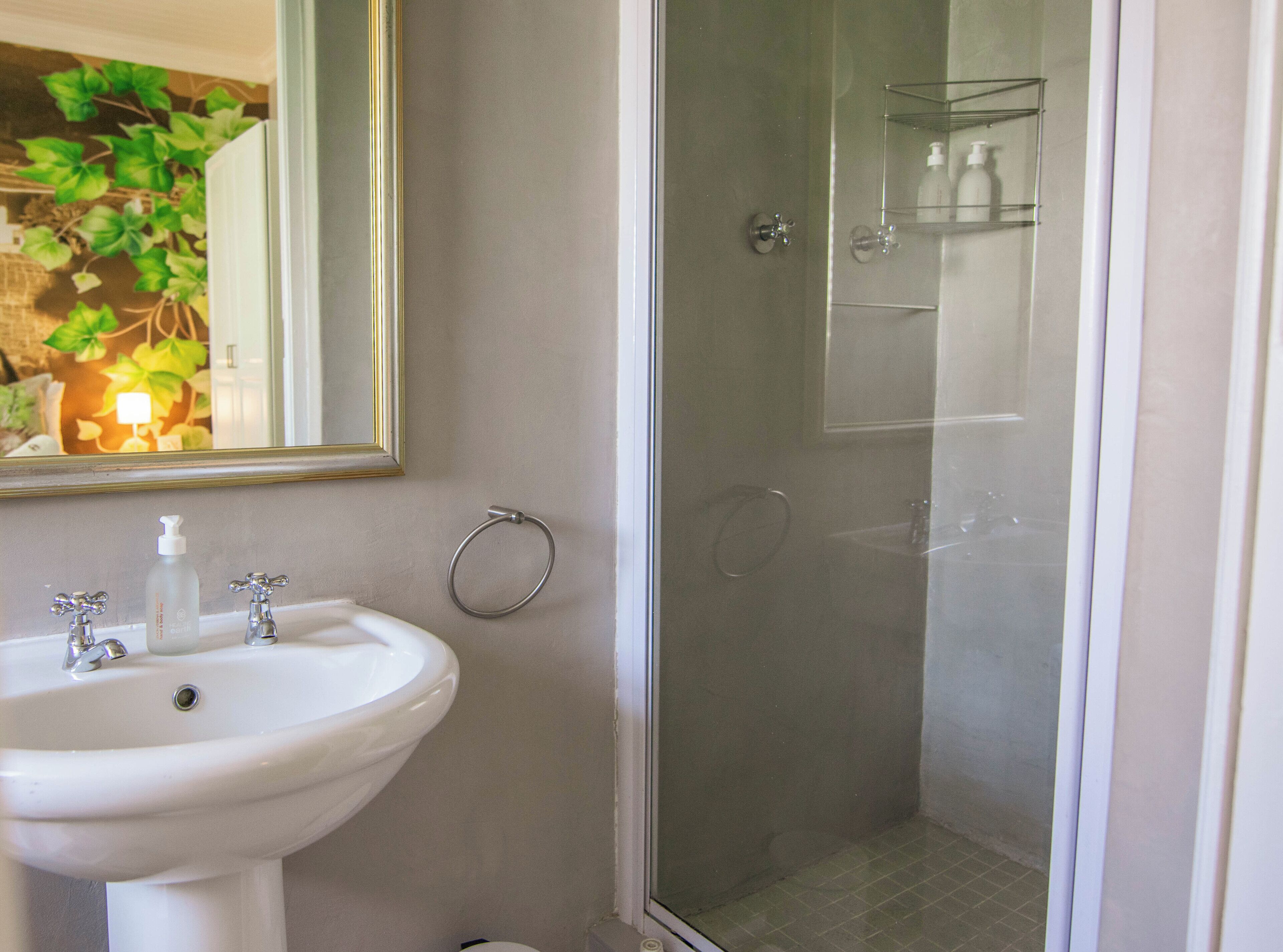 A bathroom with a sink, mirror, and shower.