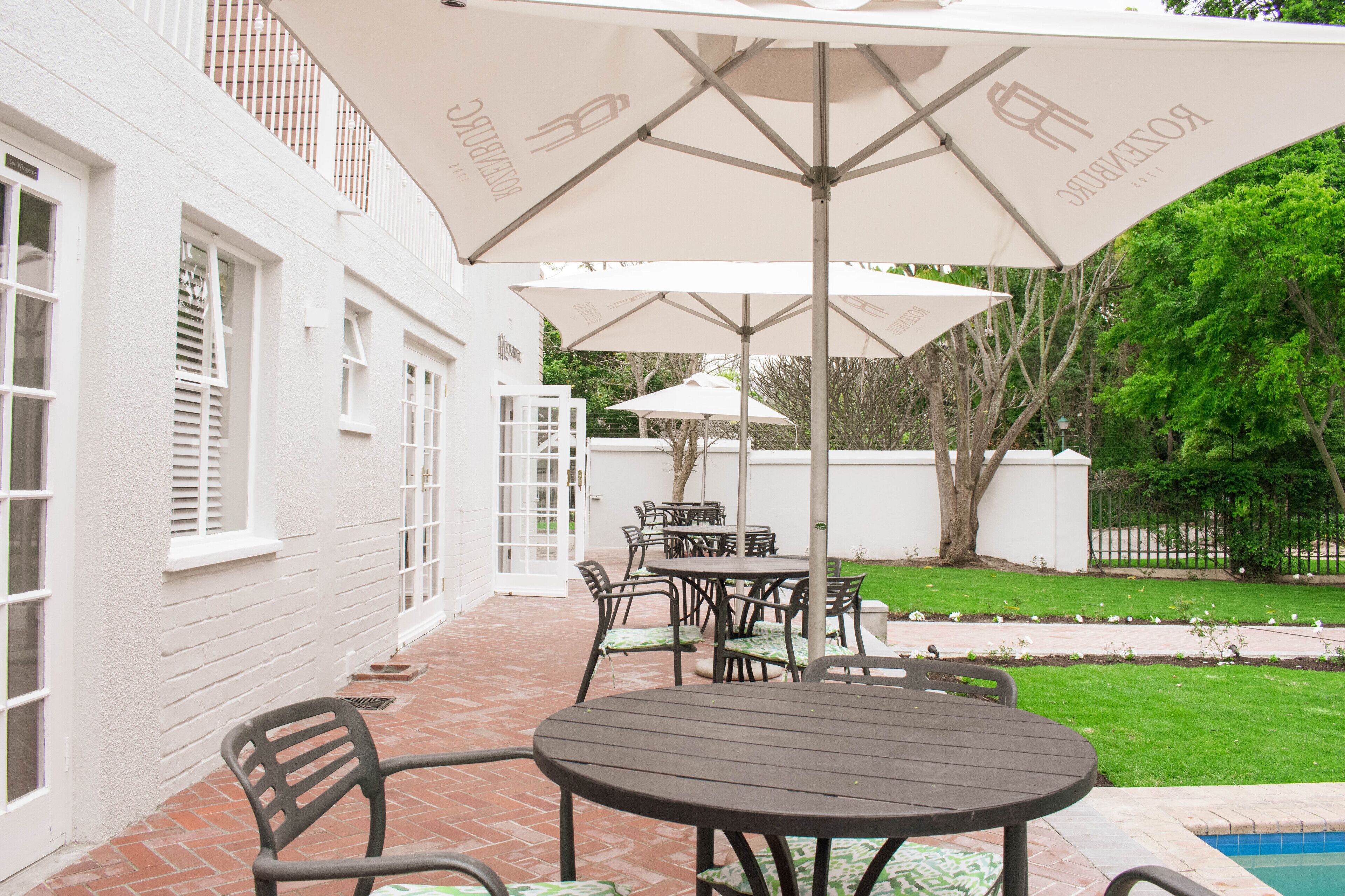 Eine Terrasse mit Billardtisch, Gartenmöbeln und Sonnenschirmen.