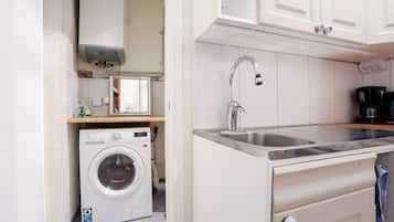A compact kitchen with a built-in washer, a stainless steel sink, and a microwave.