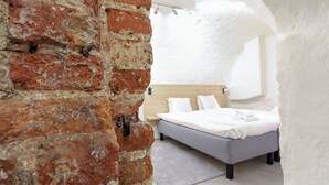 A bedroom with a brick wall, a wooden headboard, a bed with white linens, and a gray rug. - ApartDirect Gamla Stan III (Stockholm)