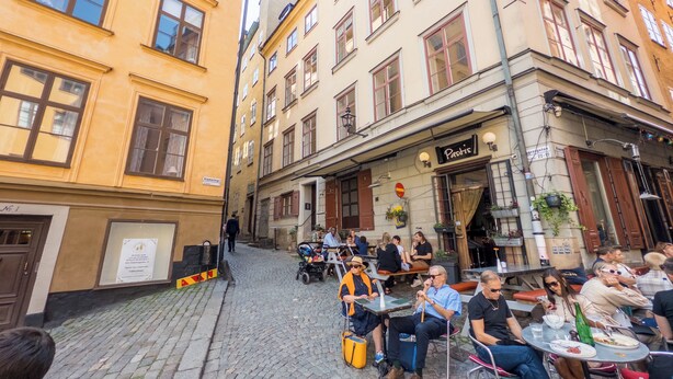 A cobblestone street with outdoor seating at a café. - ApartDirect Gamla Stan III (Stockholm)