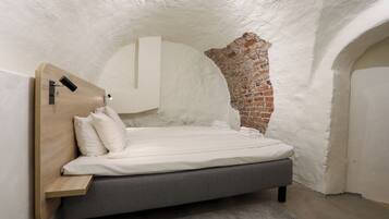Ein Schlafzimmer mit einem Bett, einem Holzkopfteil, einer Ziegelwand und einer weißen Decke.