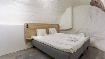 Une chambre moderne avec une tête de lit en bois, un lit gris et un mur blanc.