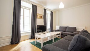 A modern living room with a grey sofa, a white coffee table, and a flat-screen TV. - ApartDirect Gamla Stan III (Stockholm)