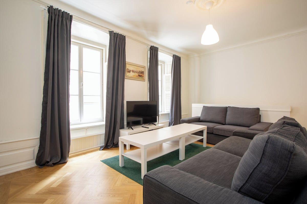 Una sala de estar moderna con un sofá gris, una mesa de centro blanca y un televisor de pantalla plana.