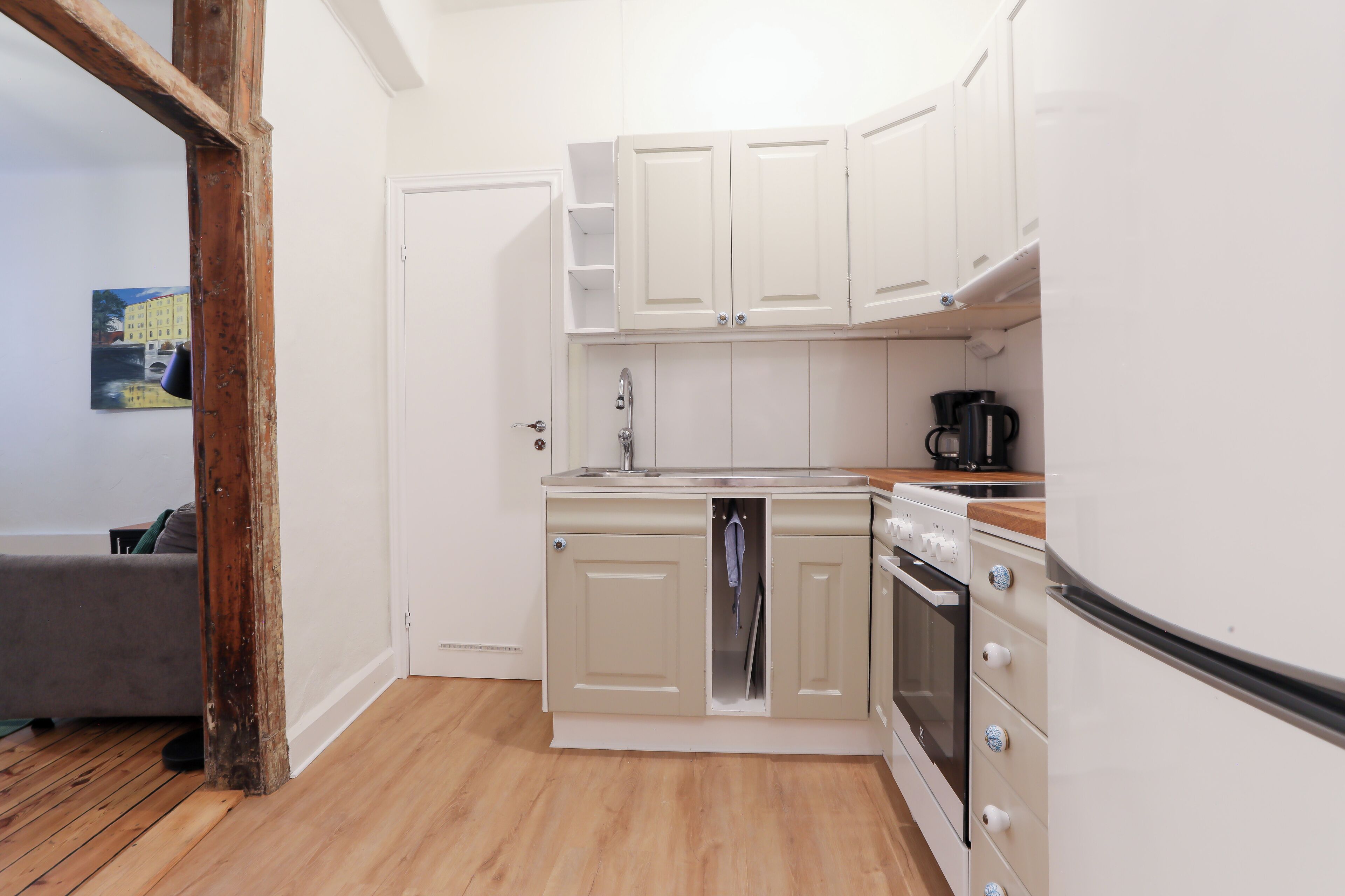 A compact kitchen with white cabinets, a built-in oven, and a refrigerator.
