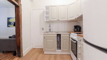 A compact kitchen with white cabinets, a built-in oven, and a refrigerator.