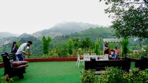 Eine Terrasse mit Blick auf grüne Hügel, ein überdachter Sitzbereich und ein Tisch mit Stühlen.