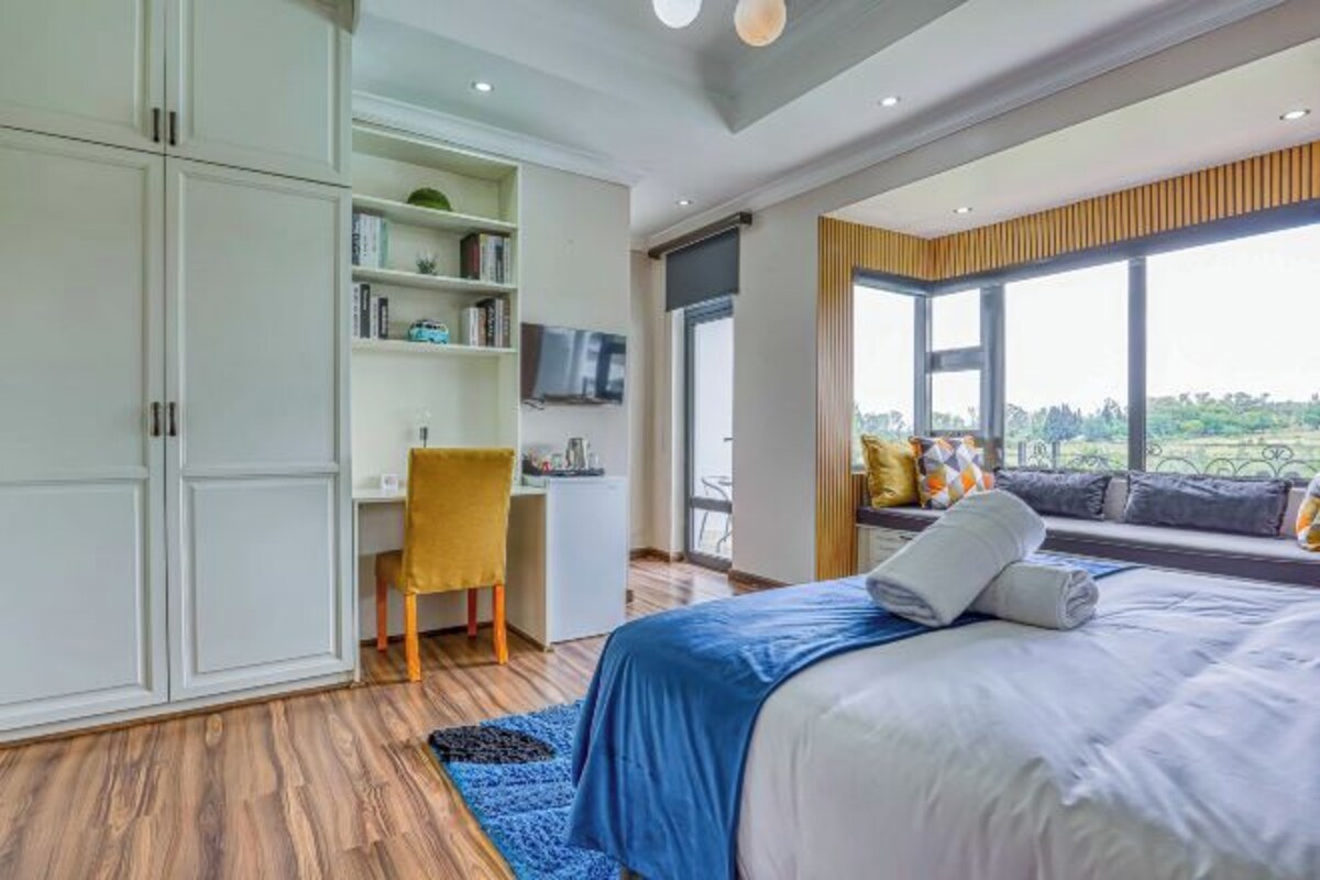 Ein modernes Schlafzimmer mit einem großen Bett, einem Schreibtisch und einem Kleiderschrank.