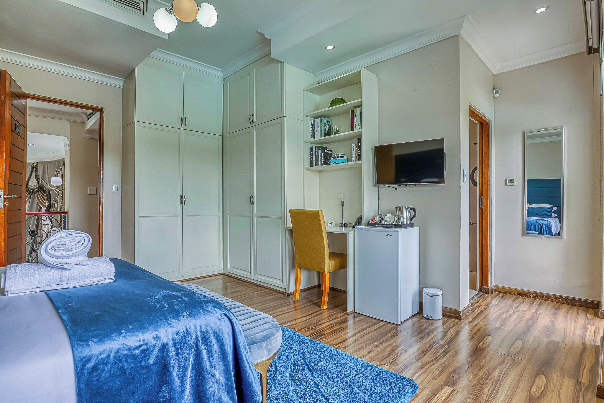 Un dormitorio con cama, escritorio, silla y televisor.