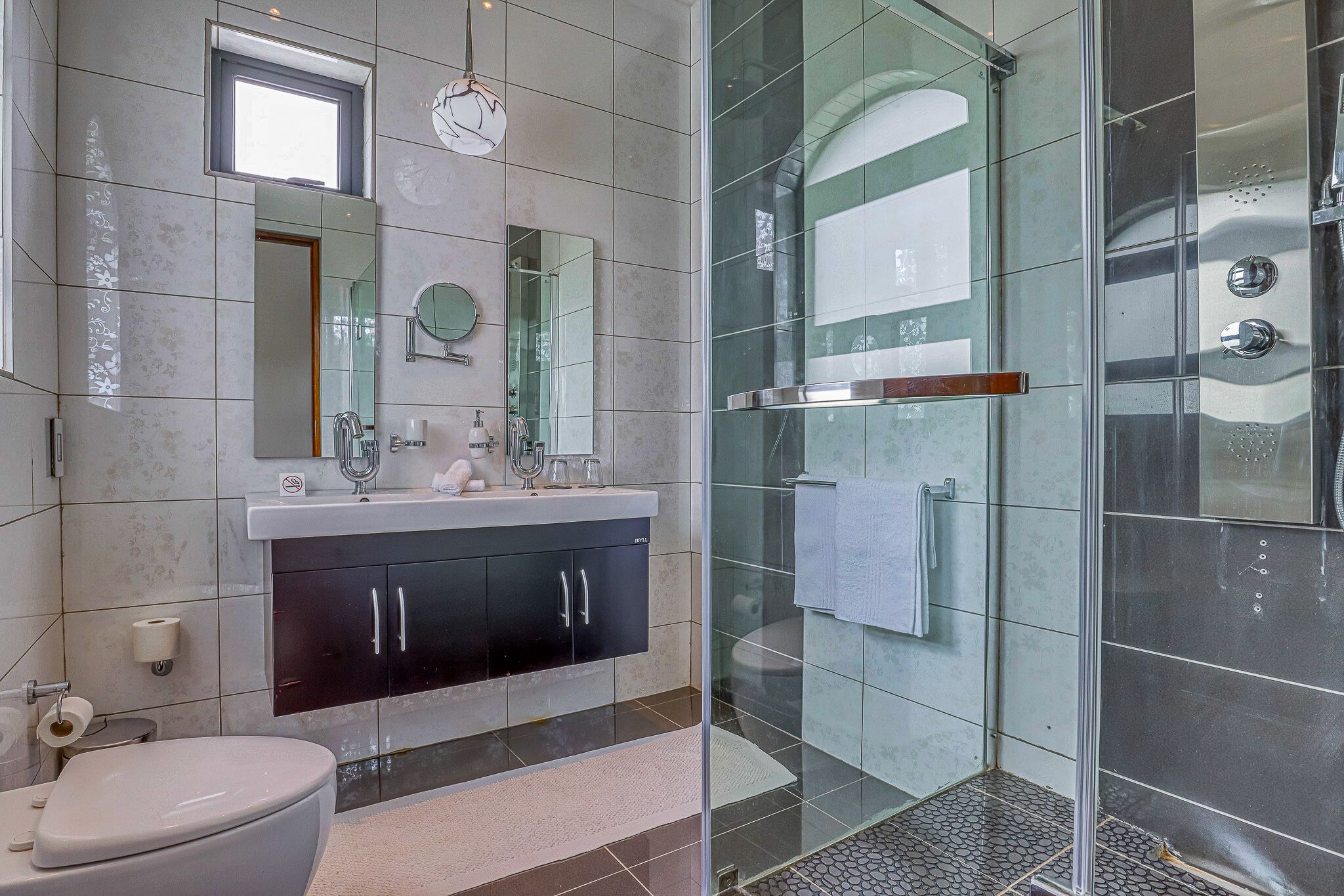 Un baño moderno con cabina de ducha de vidrio, un lavabo con espejo y un inodoro.