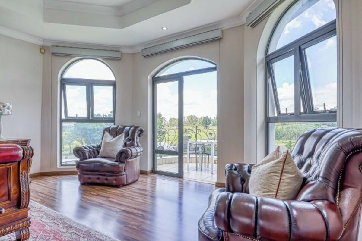 Ein geräumiges Zimmer mit großem Fenster, einem Ledersofa und einem Holzkasten.