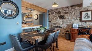 Een moderne keuken met een houten aanrecht, een eettafel met stoelen, een stenen muur en een lijst met een foto.