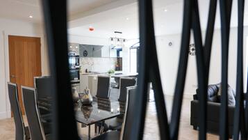 A modern kitchen with a central island, dining area with chairs, and a living room with a sofa.