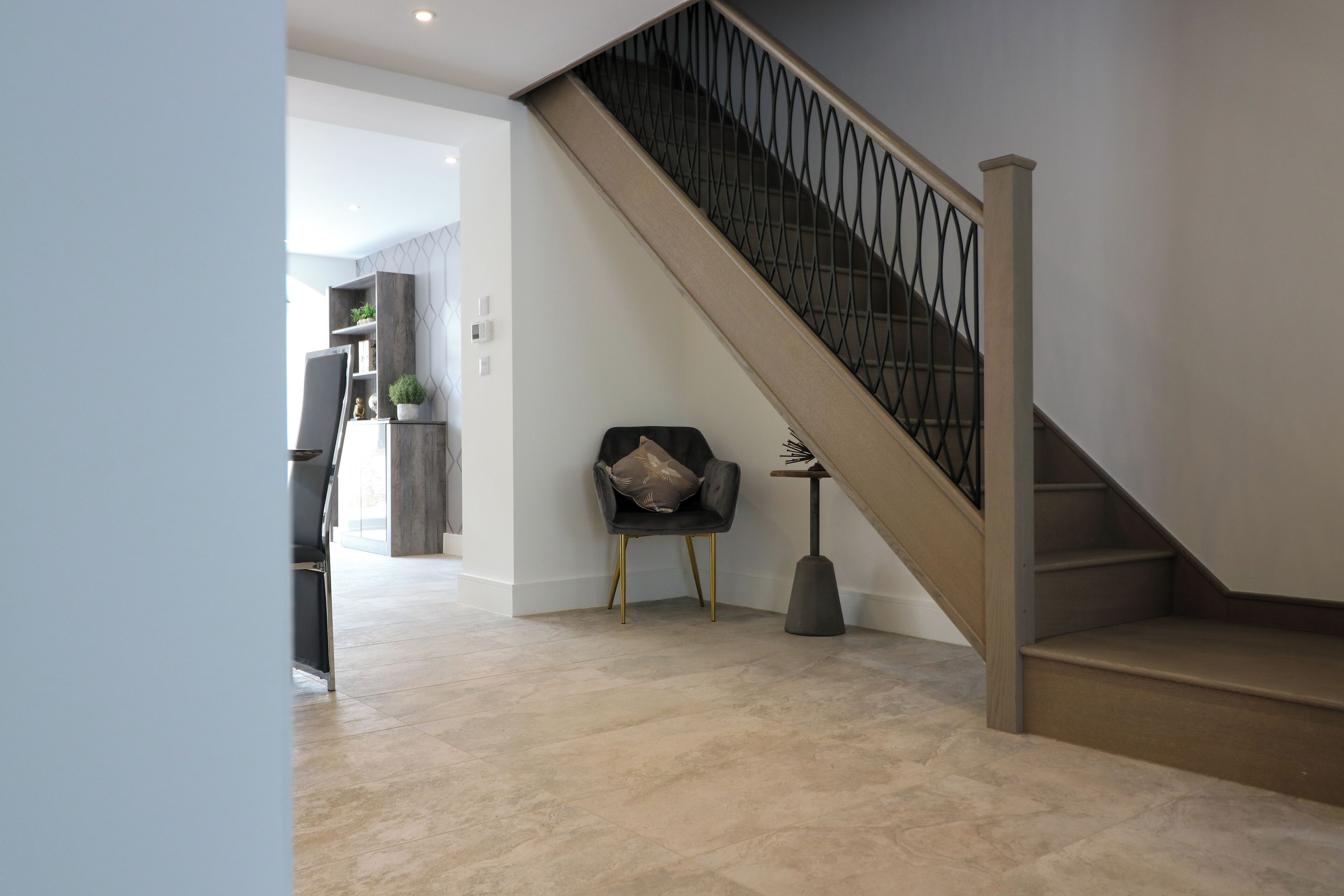 Un interior moderno con una escalera, una silla y una pequeña mesa.