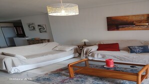 Een moderne slaapkamer met een bed, een bank, een bijzettafeltje en een hanglamp.