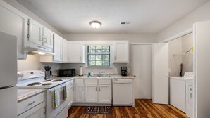 A modern kitchen with white cabinets, a stove, microwave, and a dishwasher. - Business-Ready 2 Bedroom Suite (Calhoun)