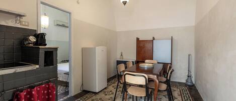 A compact kitchen with a refrigerator, a sink, and a dining table with chairs.