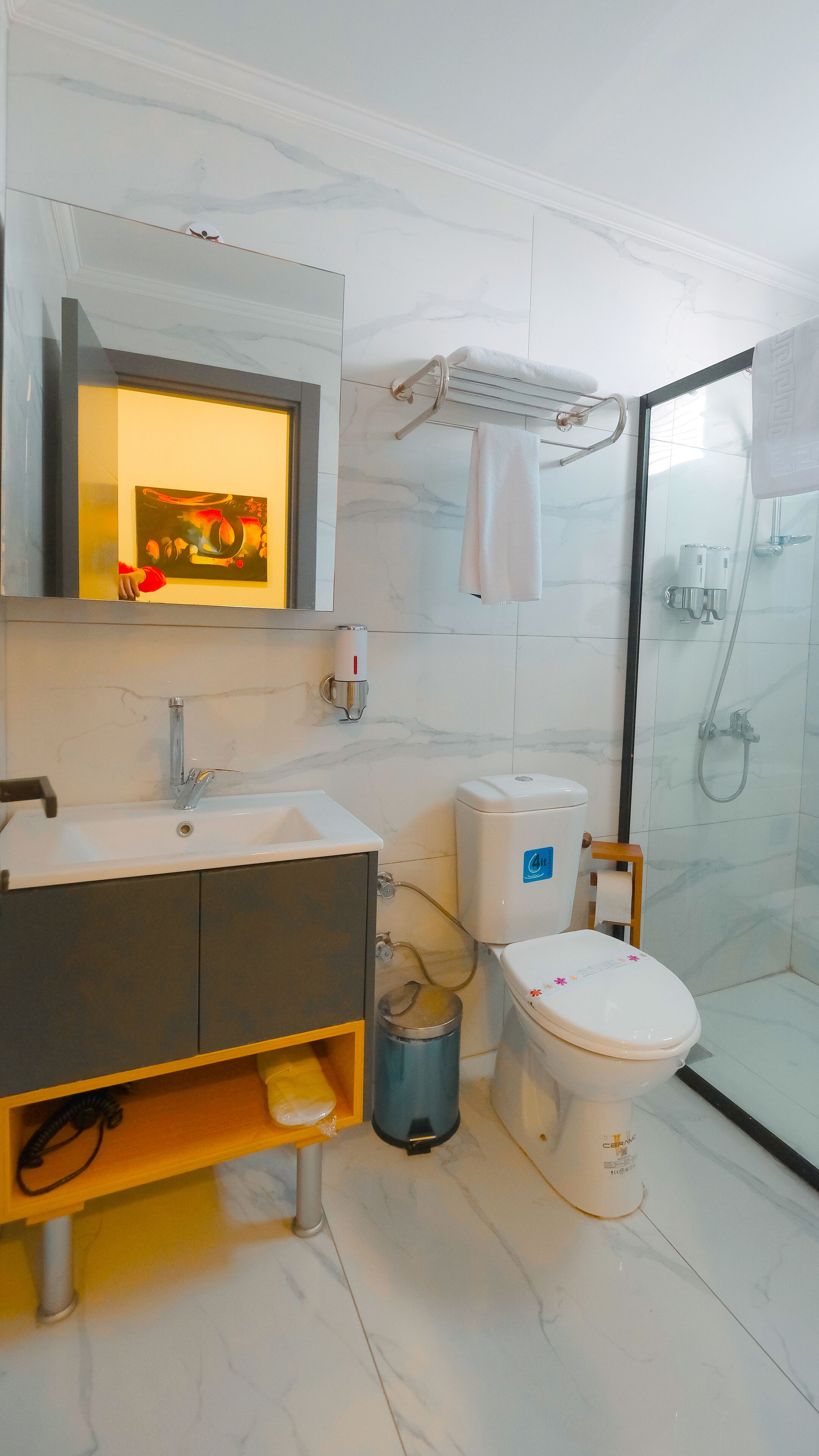 A modern bathroom with a marble sink, a toilet, and a glass-enclosed shower.