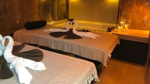 Une chambre d’hôtel avec deux lits, chacun agrémenté d’une décoration en forme de cœur réalisée avec des serviettes, et un miroir au-dessus.