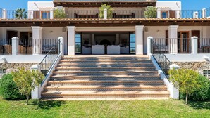 Une maison à deux étages avec une entrée centrale, un porche couvert et un escalier menant à l’entrée.