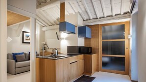 A compact kitchen with wooden cabinets, a black countertop, and a built-in microwave. - Flat Piazza del Popolo central (Roma)