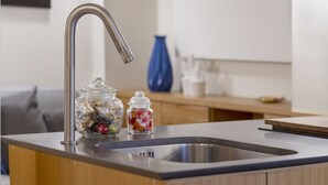 A modern kitchen with a stainless steel sink, two glass jars with lids, and a blue vase on the counter. - Flat Piazza del Popolo central (Roma)