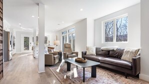 Un salon spacieux avec un canapé en cuir marron, une table basse et un tapis à motifs.