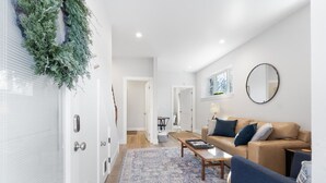 Un salon moderne avec un canapé beige, un fauteuil bleu et un tapis à motifs.
