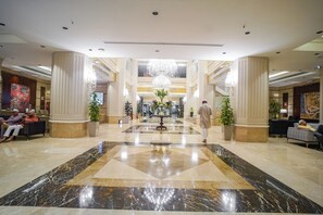 A spacious lobby with marble flooring, large columns, and a chandelier. - Emaar Al Manar (Makkah)