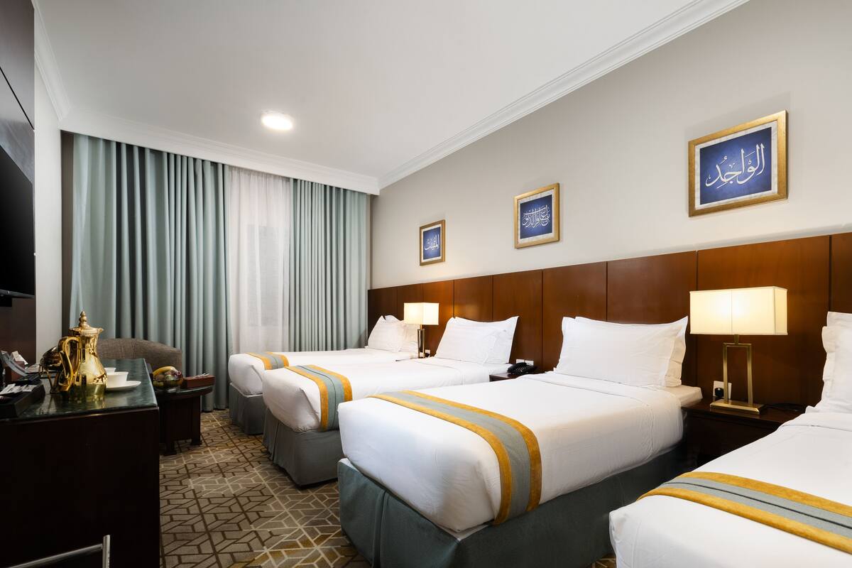 A hotel room with two beds, a desk with a telephone, a coffee maker, and a television.