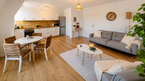 A modern living space with a dining area, sofa, and kitchen.